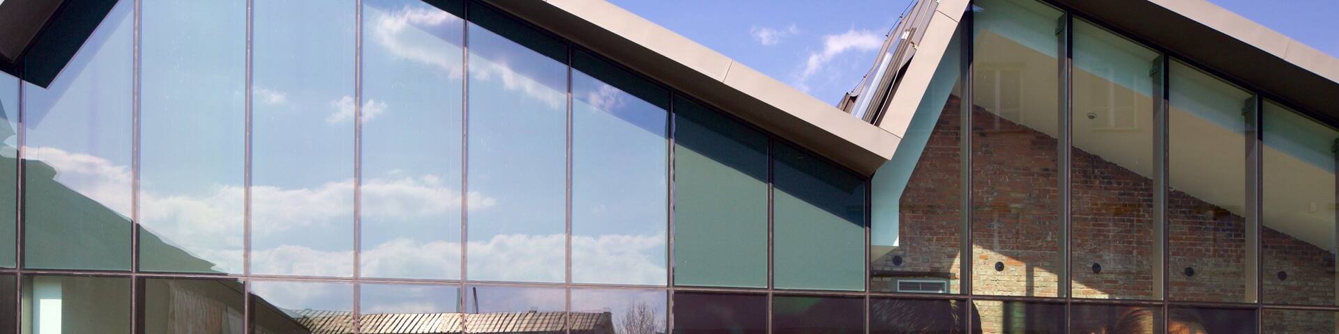 Un edificio moderno con amplios ventanales que reflejan el cielo y las nubes.