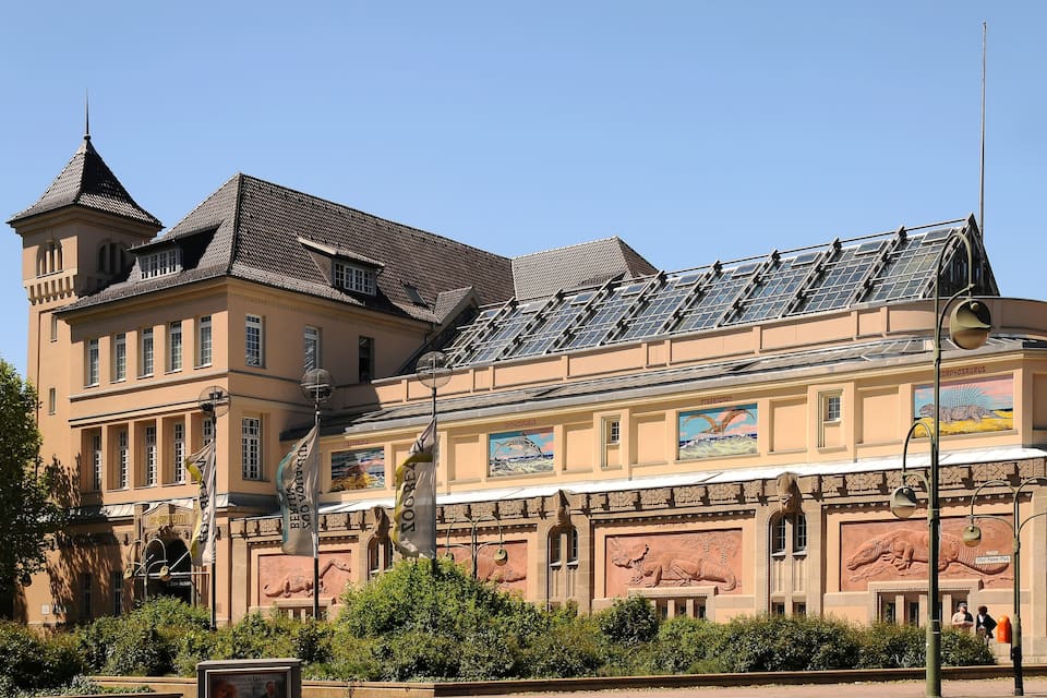 Ein historisches Gebäude mit einem Turm, Solaranlagen und Dinosaurier-Wandmalereien.