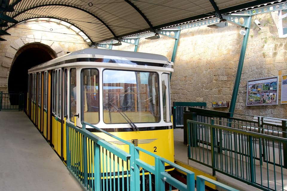Un tranvía amarillo con techo verde en una estación.