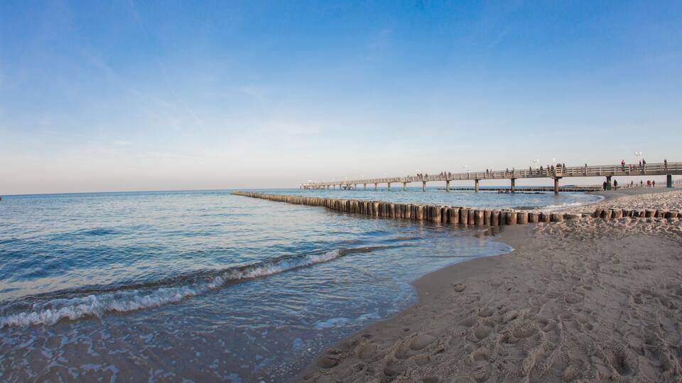 A beach with a wooden pier extending into the ocean.