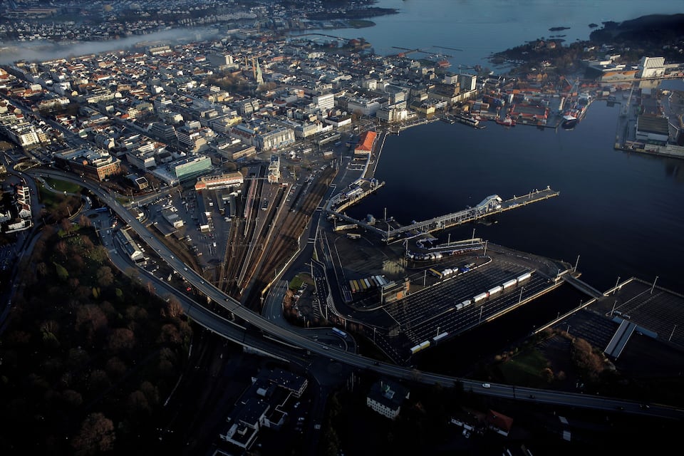An aerial view of a coastal city with a marina, a large stadium, and a complex highway interchange.