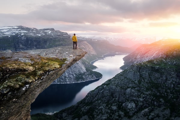 Alone tourist on Trolltunga rock - most spectacular and famous scenic cliff in Norway