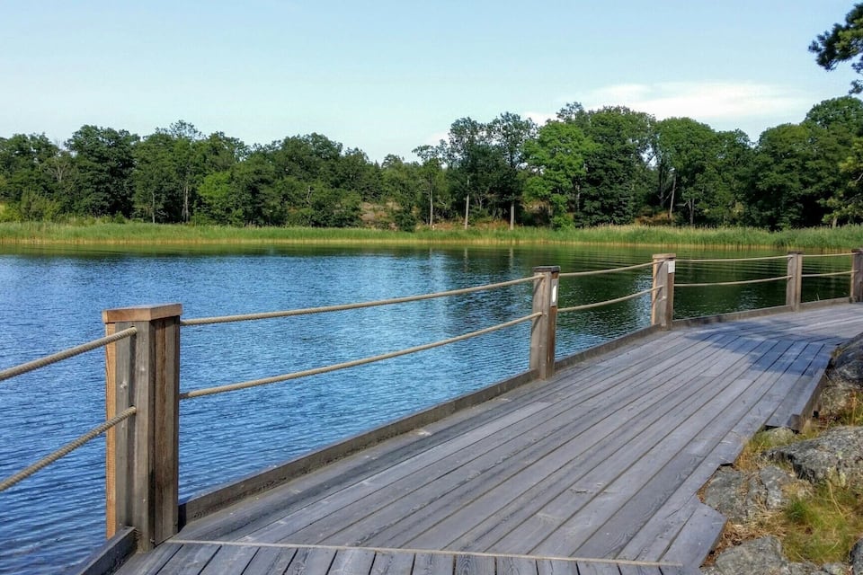 Une promenade en bois longe un lac paisible, bordé d’une forêt dense.