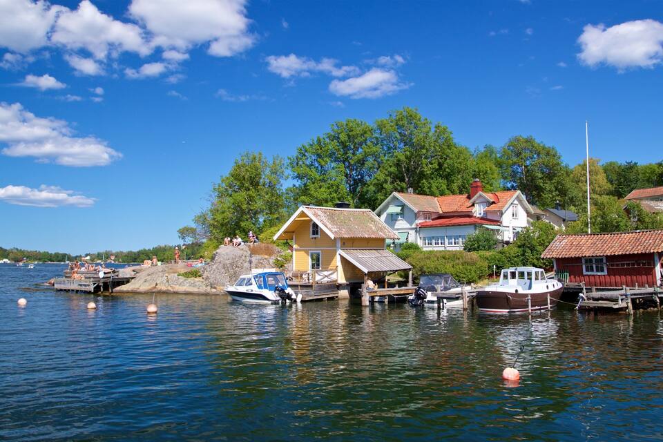 A lakeside village with houses, boats, and a clear blue sky.