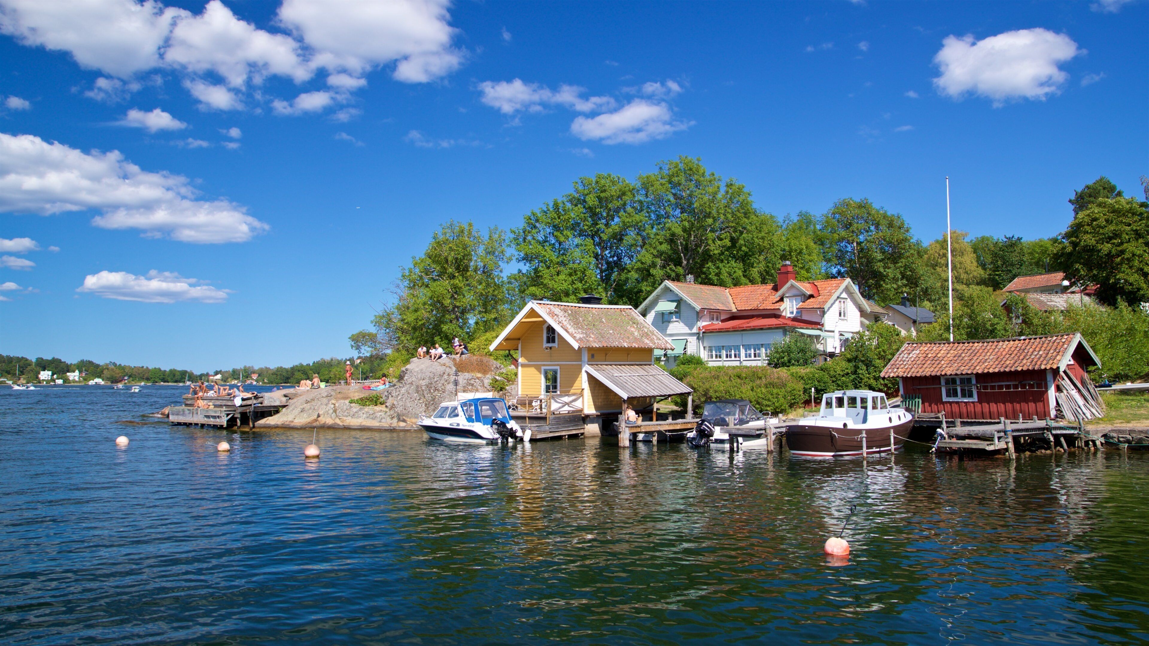 A lakeside village with houses, boats, and a clear blue sky.