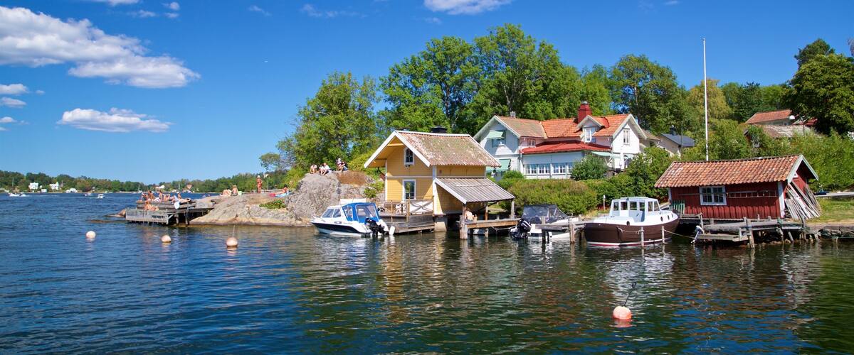 A lakeside village with houses, boats, and a clear blue sky.
