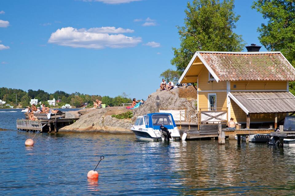 Een uitzicht op een meer met een geel huis, een steiger en een boot.