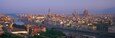 Ein weiter Panoramablick auf eine historische Stadt mit einem markanten Dom, einem Fluss und einer Brücke.