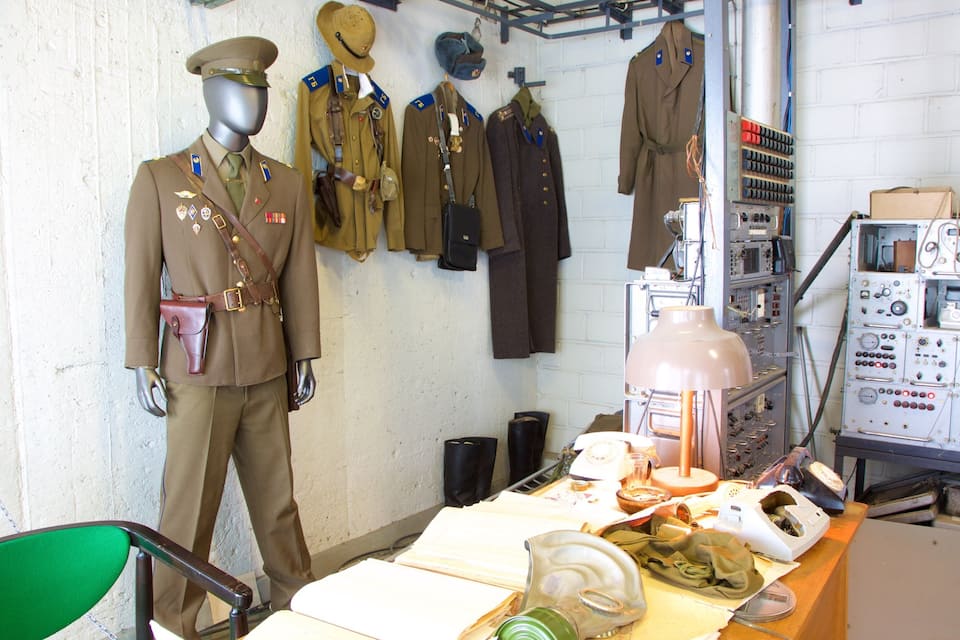 A military uniform display with mannequins and various uniforms on a wall.