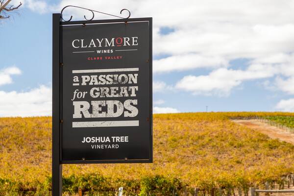 Schild für Claymore Wines in Clare Valley, Joshua Tree Vineyard, mit einem Weinberg im Hintergrund.