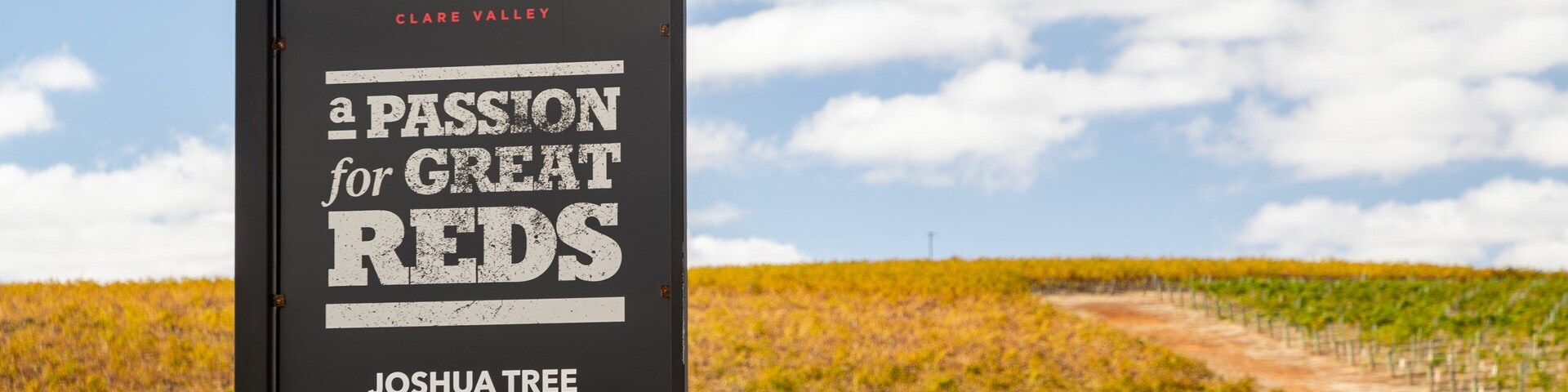 Señal de Claymore Wines en Clare Valley, Viñedo Joshua Tree, con un viñedo de fondo.
