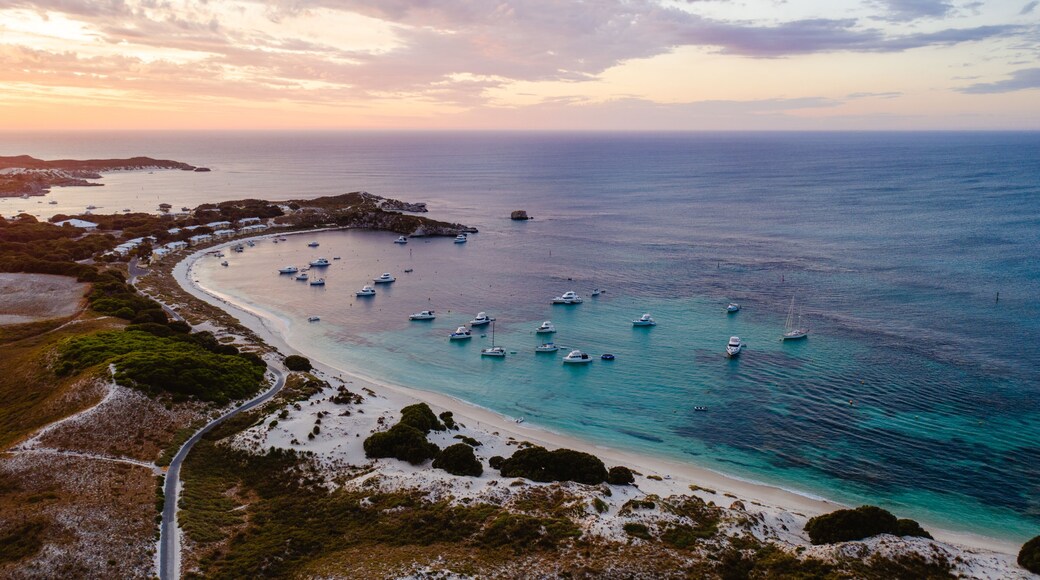 Aerial drone shot of a magical sunset over Rottnest Island, Perth, Western Australia. Geordie Bay below with luxury boats and yachts.