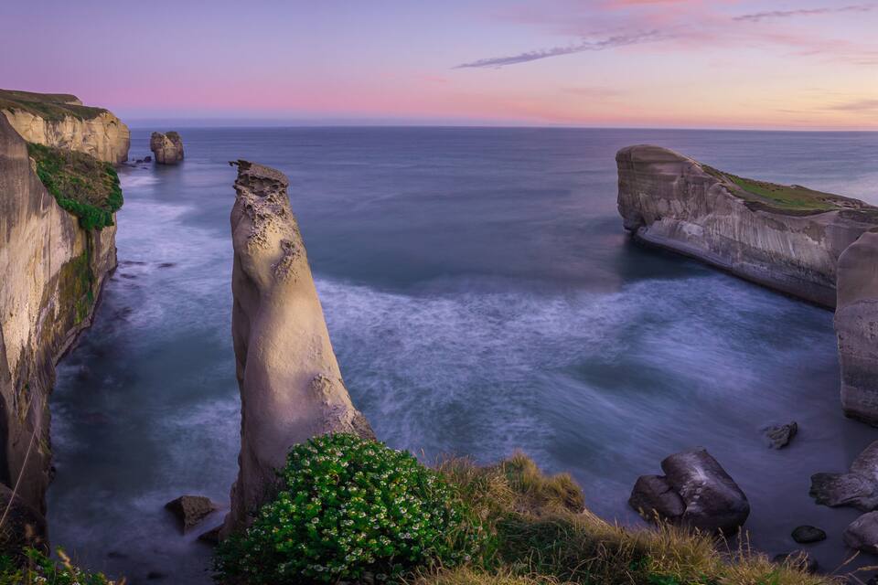 A coastal landscape with a prominent rock formation and cliffs.