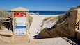A beach entrance sign with warnings and regulations.