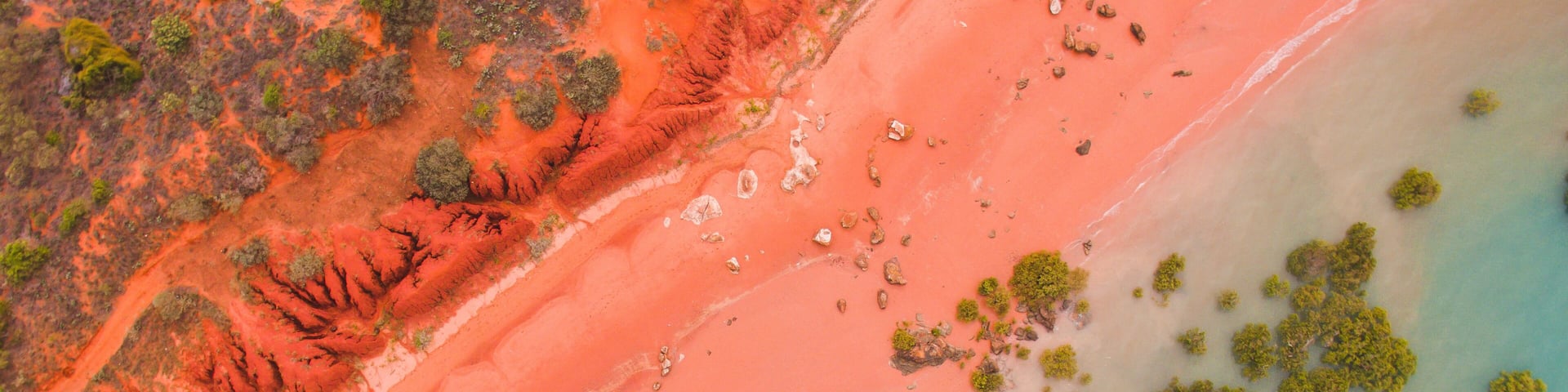 Roebuck bay in broome, western australia as seen from the air. SHowing the pink beach, red cliffs, turquoise water and green mangroves.