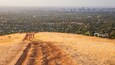 A hilly landscape with a dirt path leading towards a city.