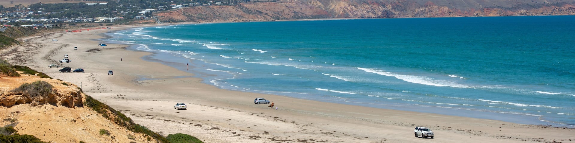 A coastal landscape with a beach, ocean, and distant hills.