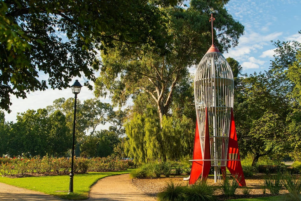 A park with a rocket sculpture, a lamp post, and a pathway.