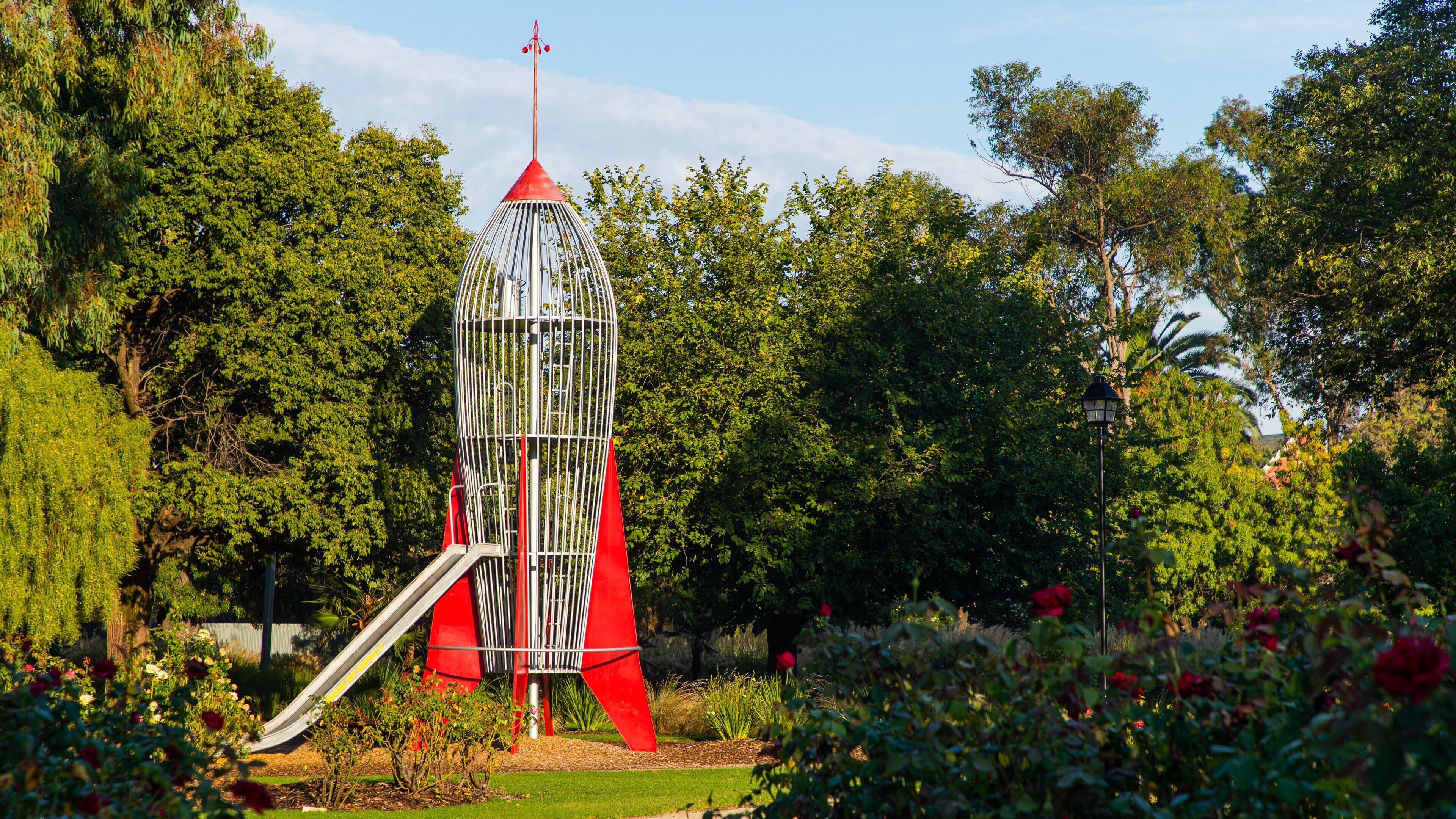 A red and white tower-like structure with a slide in a park.
