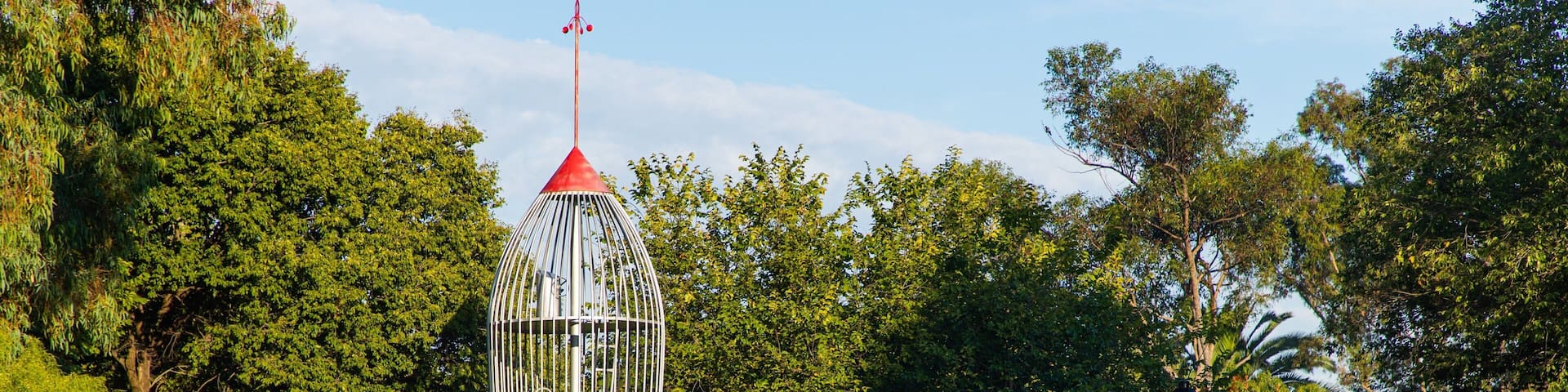 A red and white tower-like structure with a slide in a park.