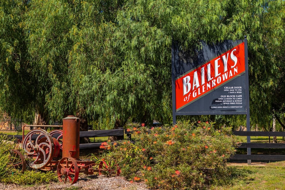 A sign for Bailey's of Glenrowan with details about the cellar door and Old Block Café hours.