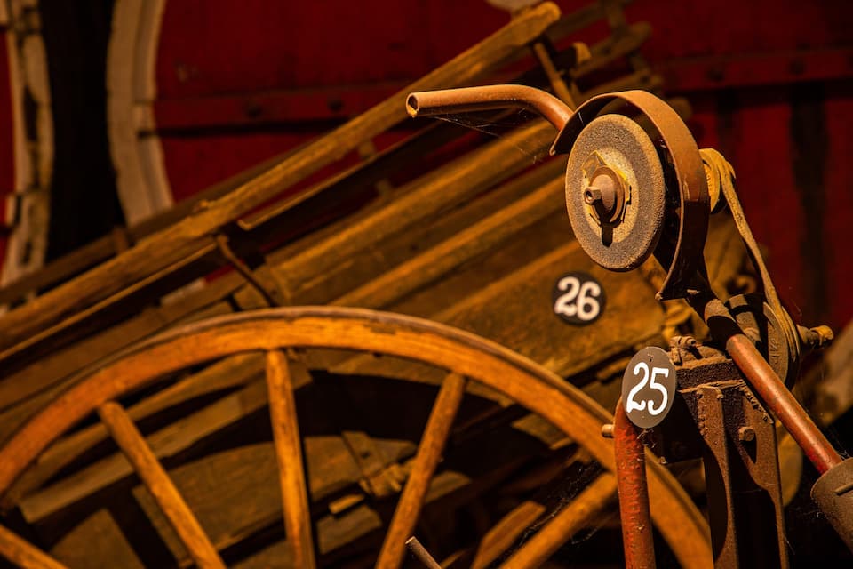 A vintage wooden cart with metal parts, wheels, and numbers 25 and 26 visible.