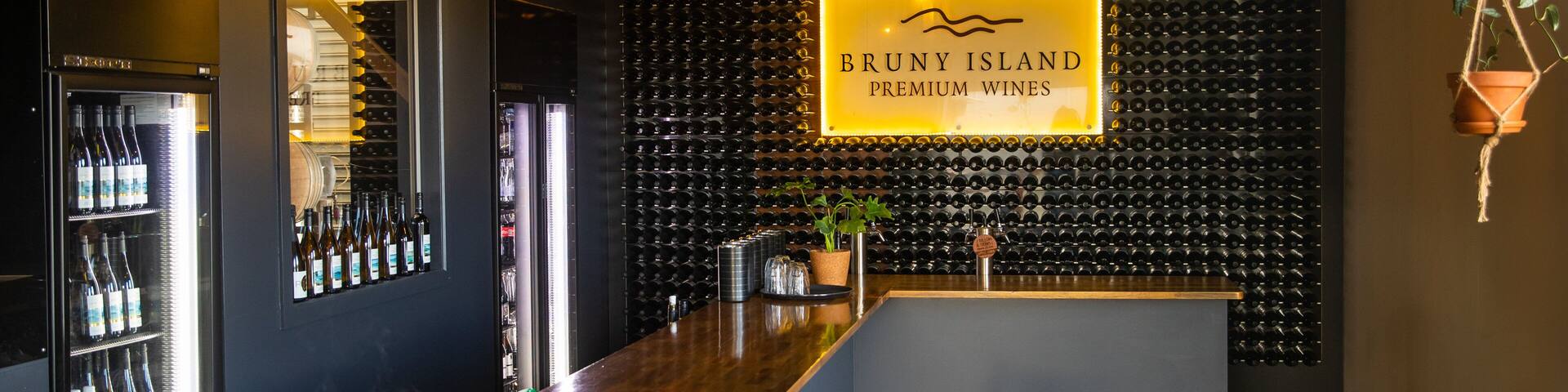 A bar with a sign reading "BRUNY ISLAND PREMIUM WINES" and a wall of wine bottles.