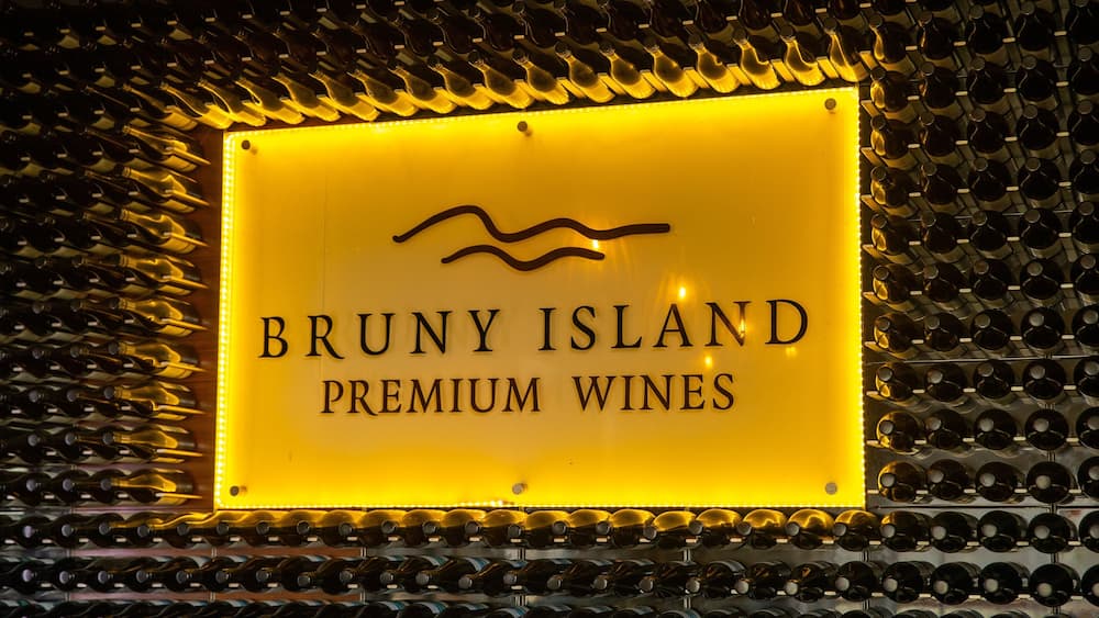 A sign for Bruny Island Premium Wines with a backdrop of wine bottles.