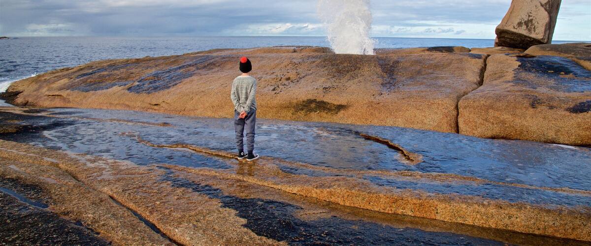 Bicheno Blowhole which includes general coastal views and rugged coastline as well as an individual child