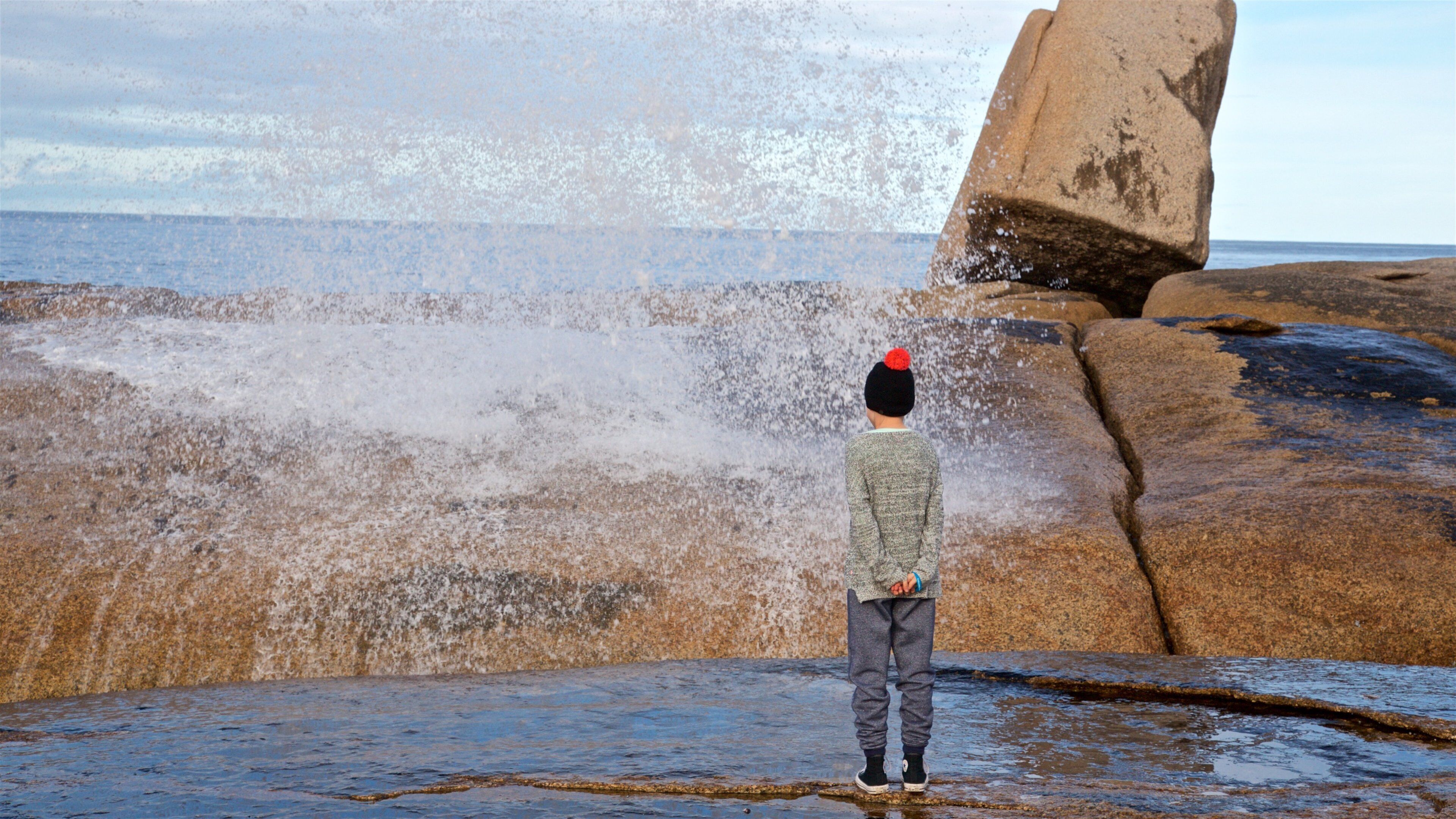 Bicheno Blowhole featuring general coastal views and rugged coastline as well as an individual child