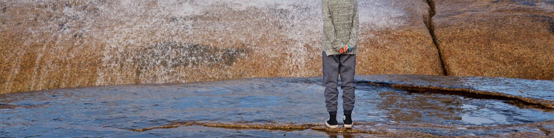 Bicheno Blowhole featuring general coastal views and rugged coastline as well as an individual child