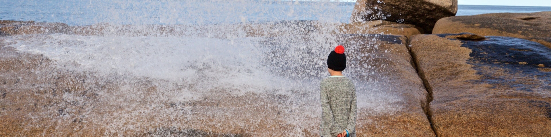 Bicheno Blowhole featuring general coastal views and rugged coastline as well as an individual child
