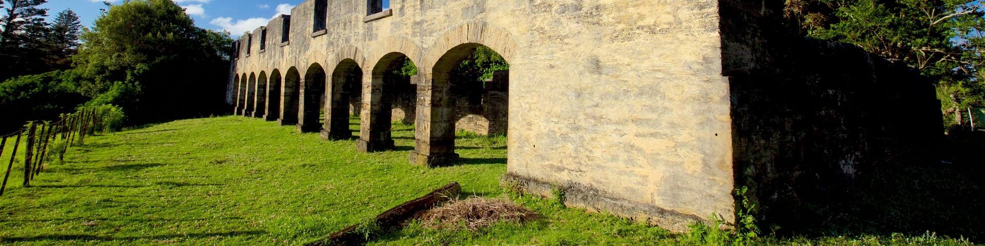 A stone structure with arches and a grassy slope.