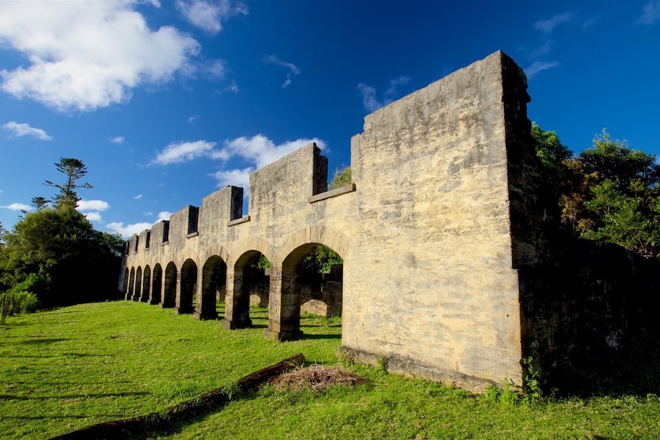 A stone structure with arches and a grassy slope.