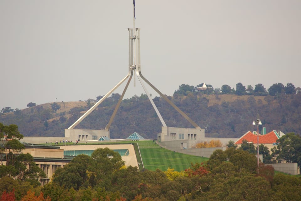 A modern bridge with a unique triangular design, surrounded by lush greenery and hills in the background.