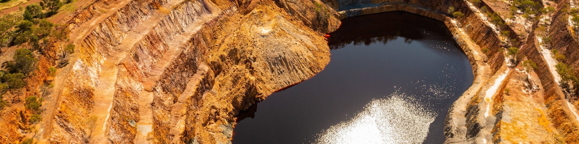 A large open-pit mine with terraced walls and a central water body.