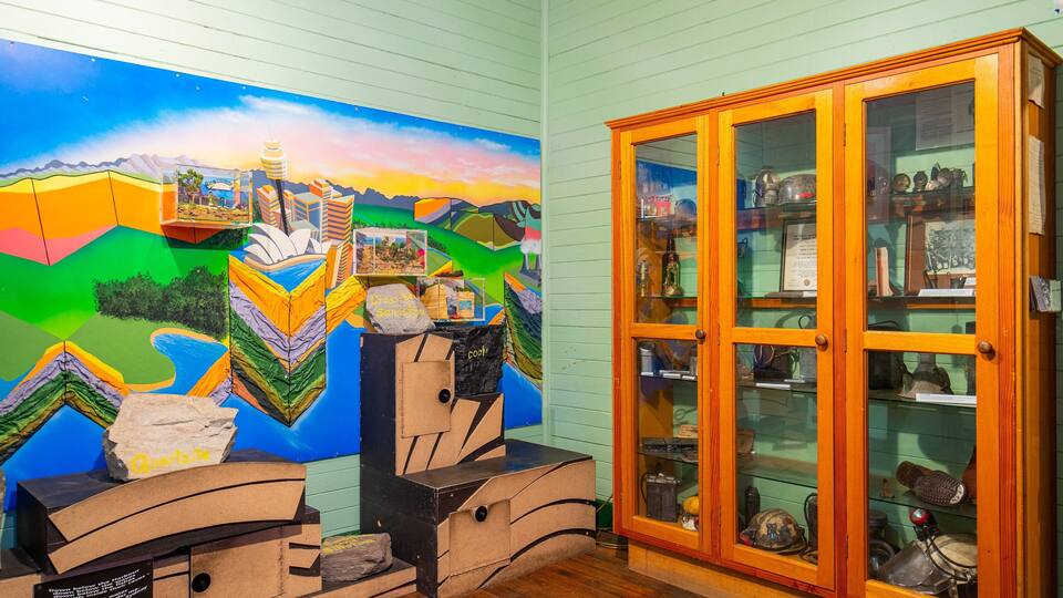 A colorful mural, a wooden cabinet with glass doors, and various geological specimens.