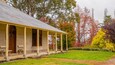 A rustic house with a porch, surrounded by autumn-colored trees.