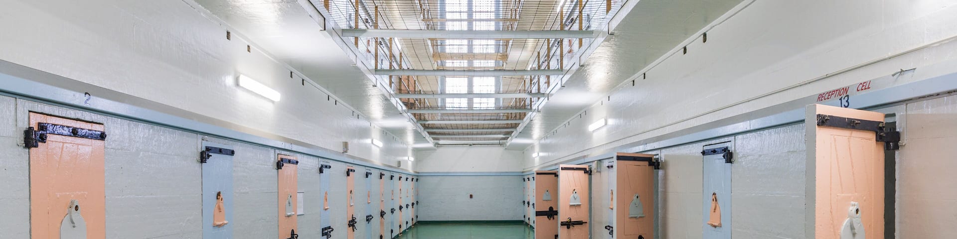 A row of lockers with benches in a well-lit, green-floored hallway.