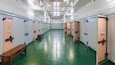 A row of lockers with benches in a well-lit, green-floored hallway.
