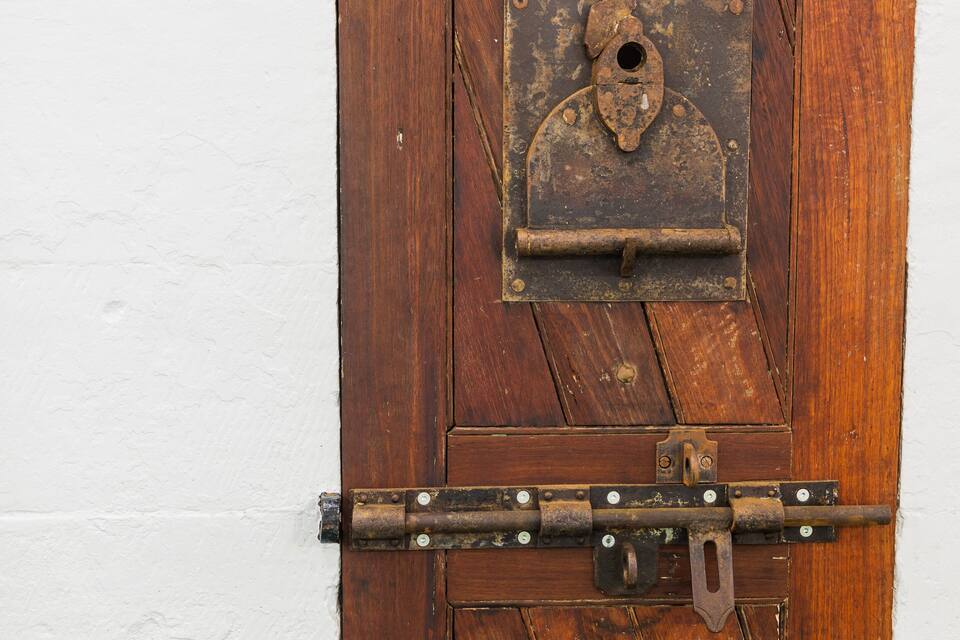 A rustic wooden door with a metal latch and a small, weathered window.
