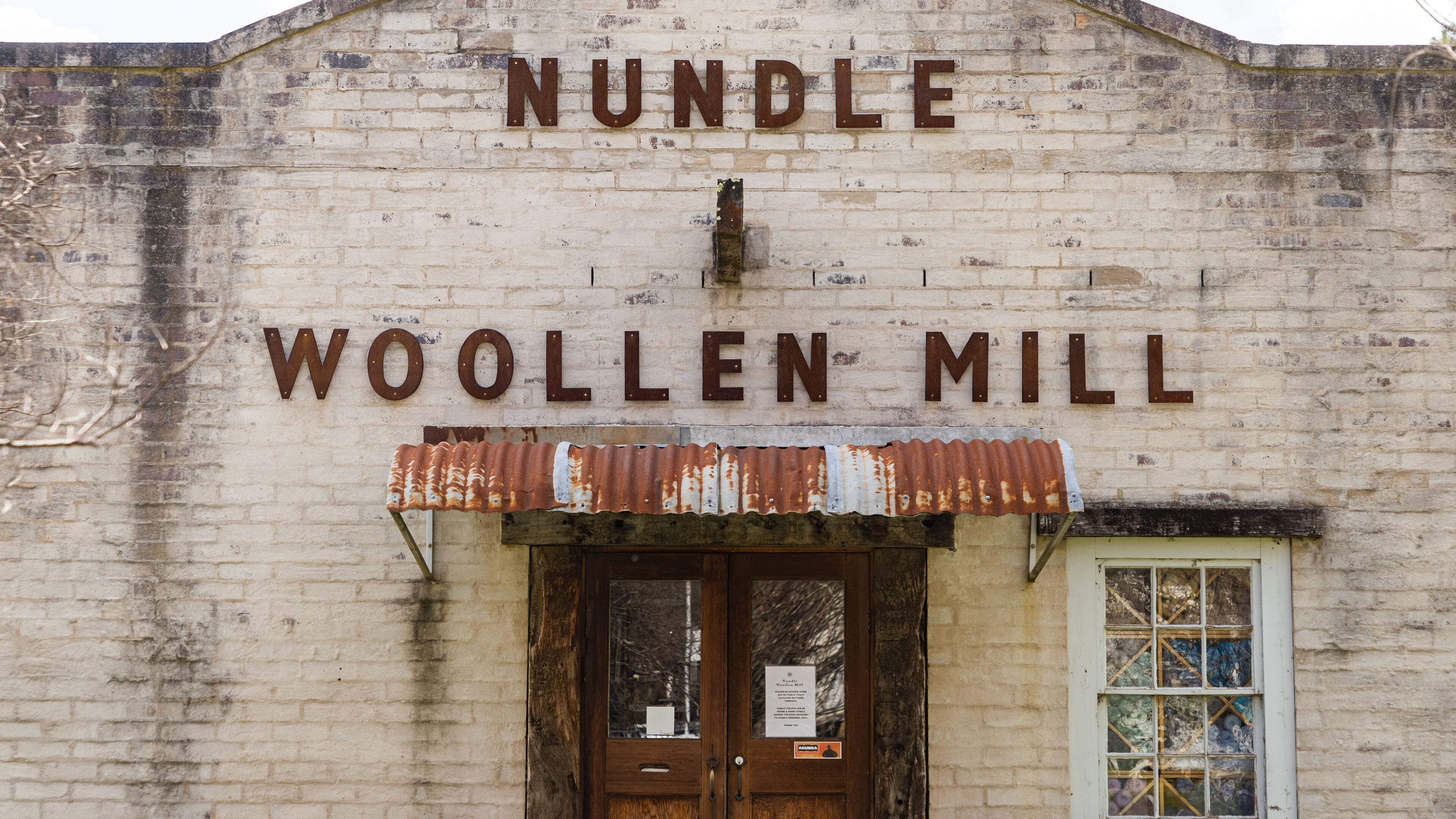 A weathered building with the sign "NUNBLE WOOLLEN MILL".