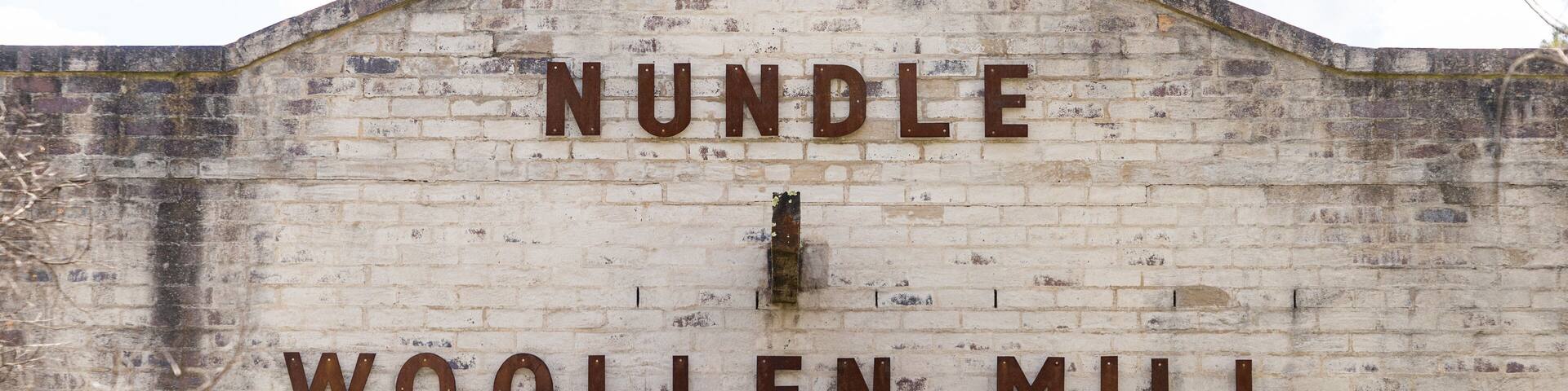 A weathered building with the sign "NUNBLE WOOLLEN MILL".