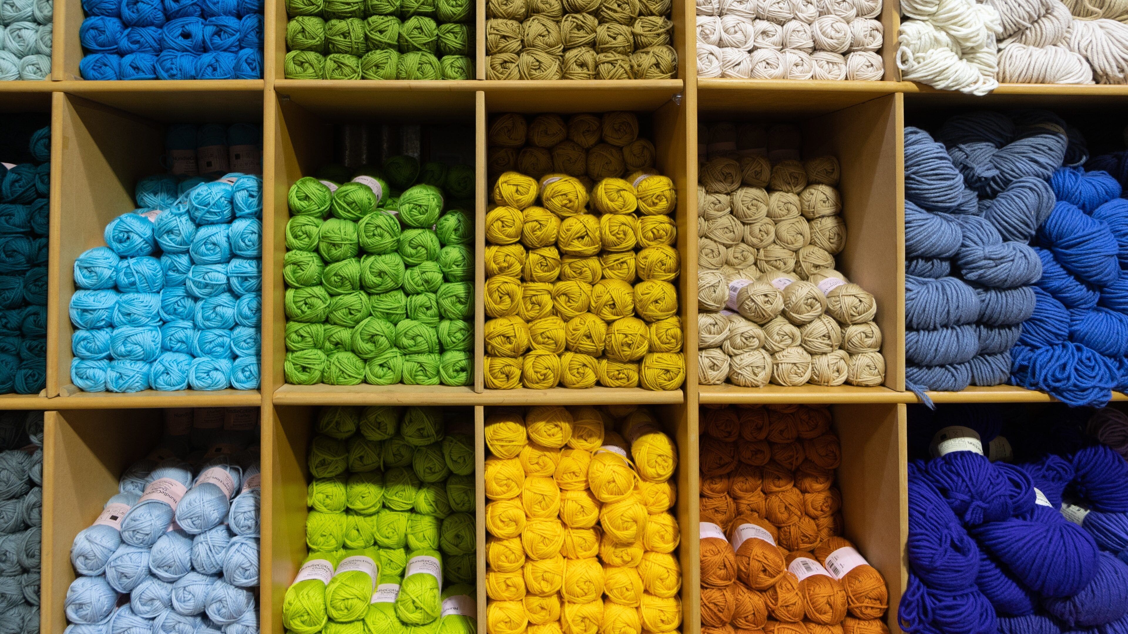 A display of yarn in various colors arranged in wooden boxes.