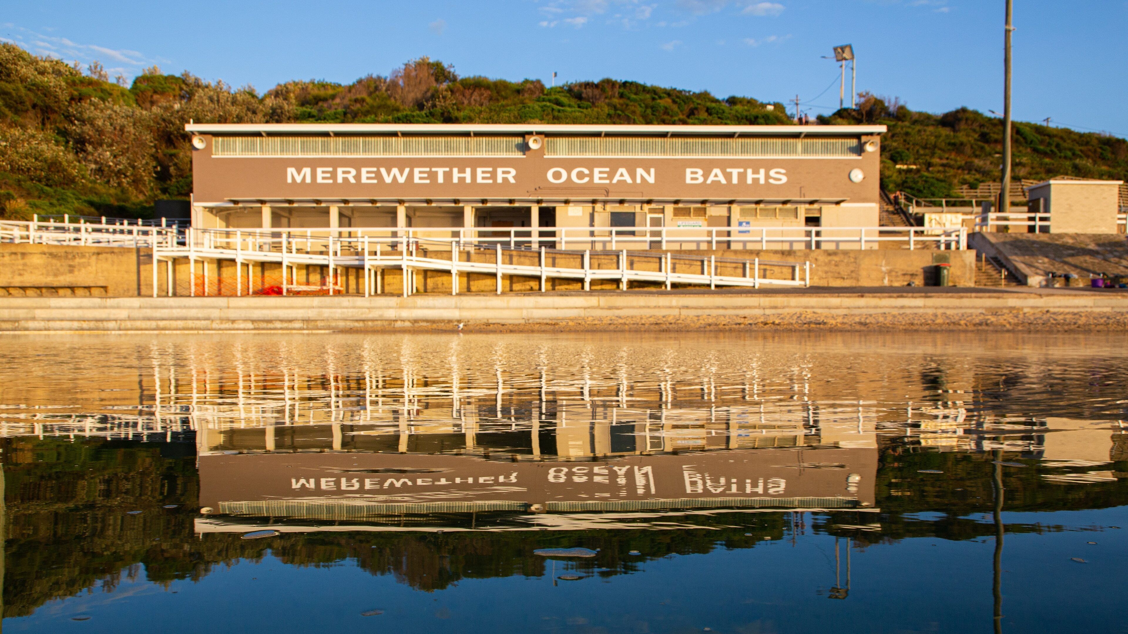 A building labeled "Merewether Ocean Baths" with a reflection in the water.