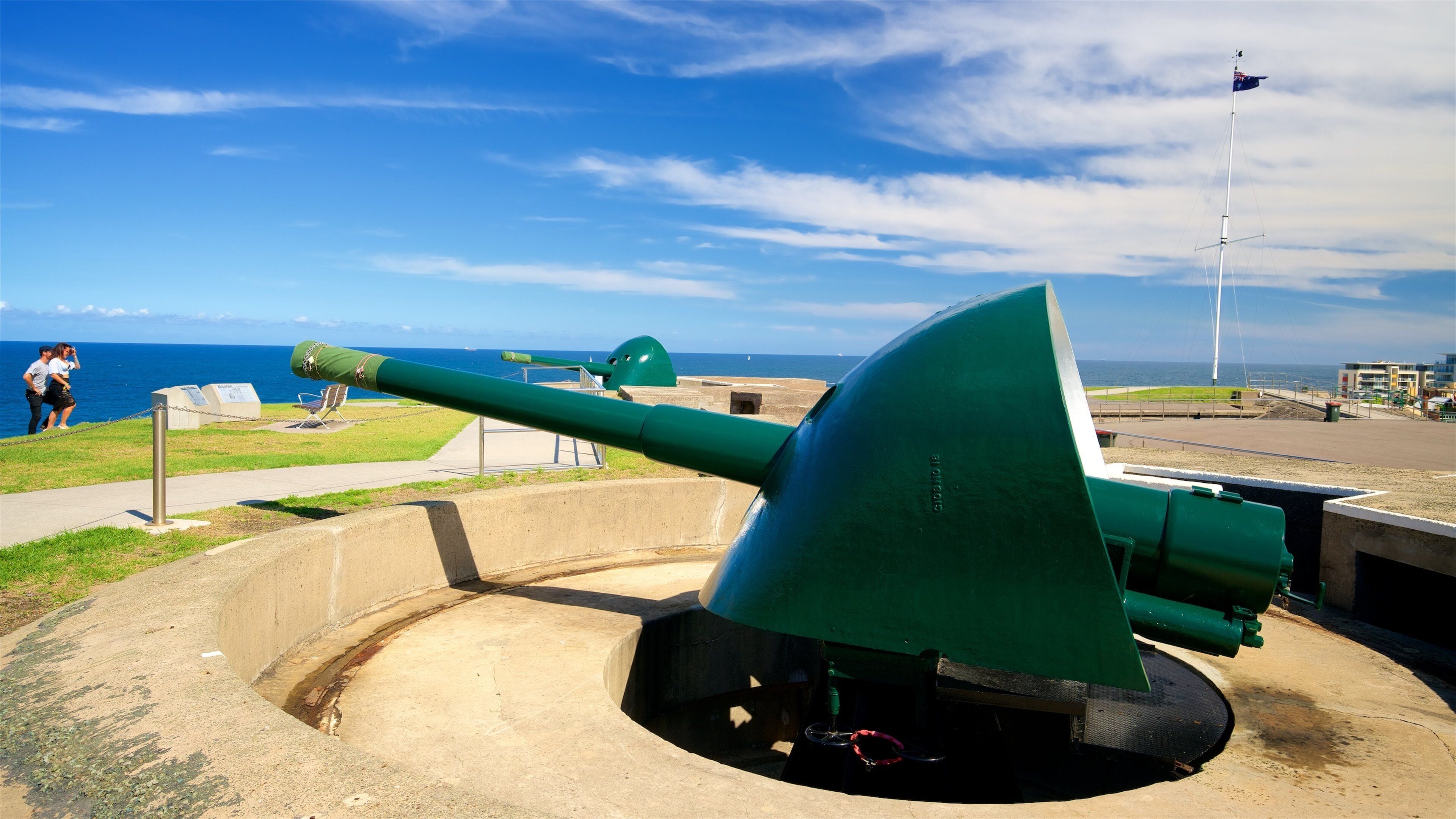 Um canhão verde numa estrutura de concreto com vista para o oceano e céu claro.