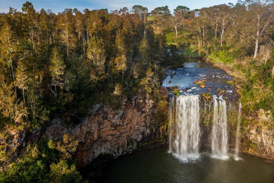 A waterfall cascading down a rocky cliff surrounded by dense forest.