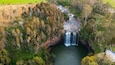 A waterfall cascading into a river surrounded by dense forest.