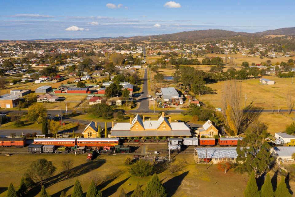 A town with a prominent train station, railway tracks, and surrounding residential and commercial buildings.