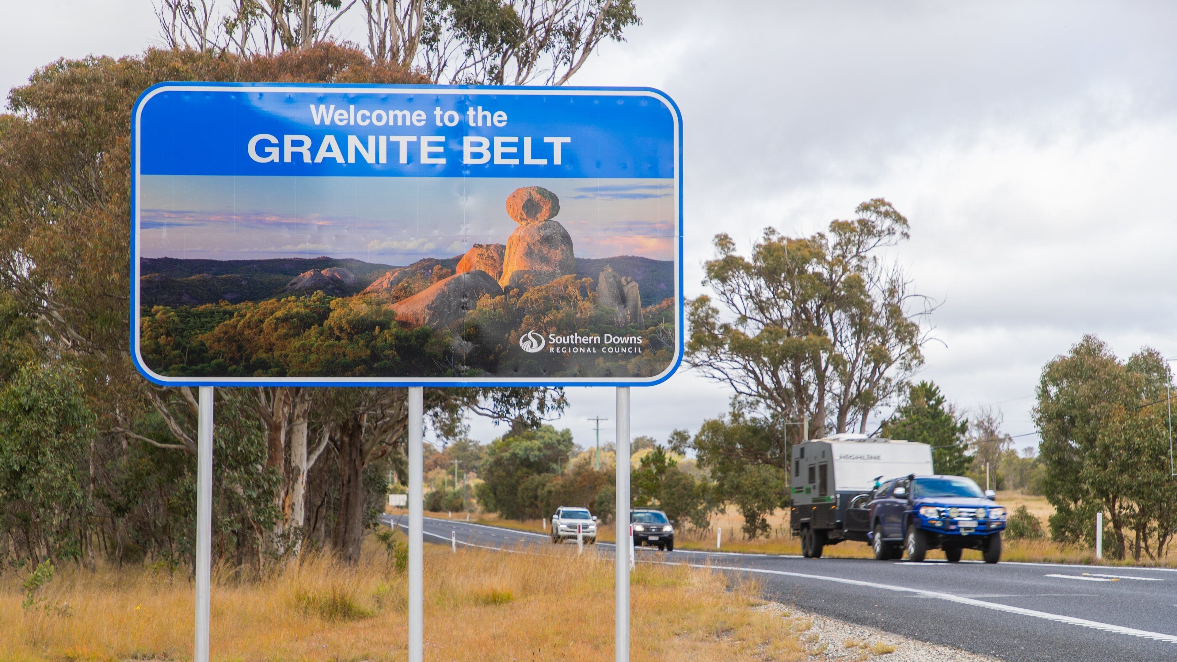 Un cartel de bienvenida da la bienvenida a visitantes a la región de Granite Belt, mostrando un paisaje pintoresco.